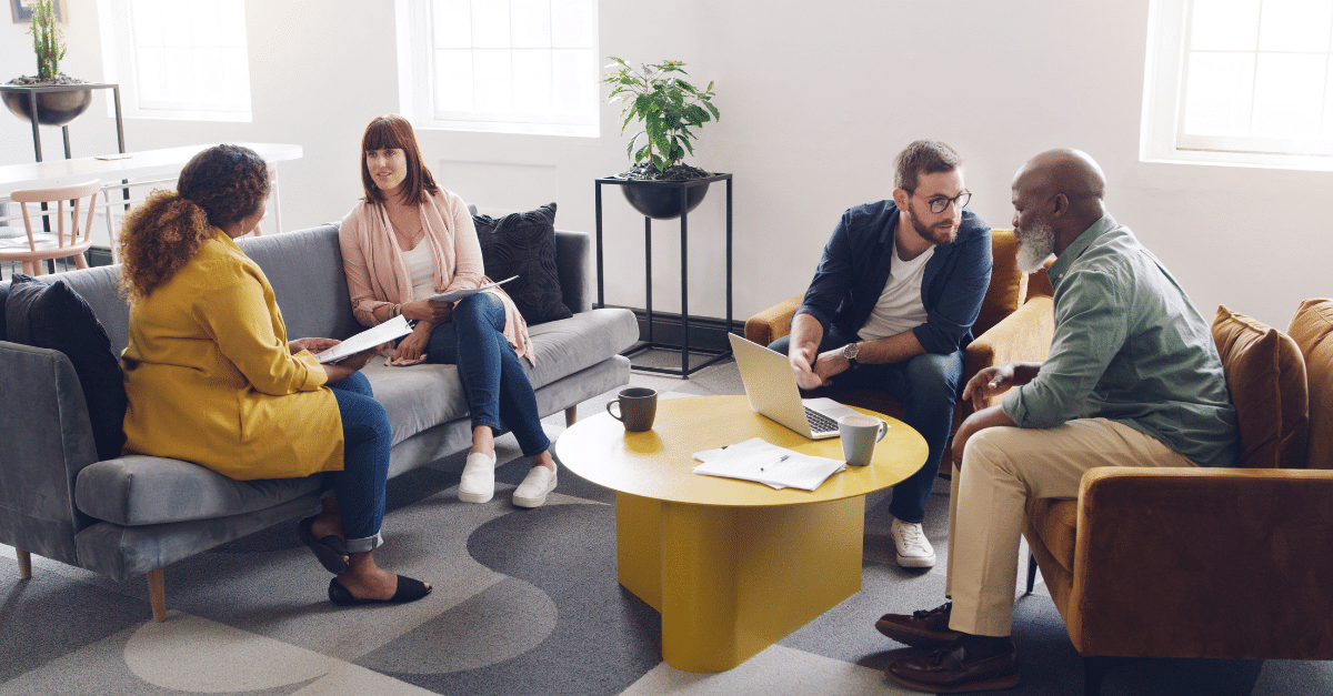 A group of four professionals in a casual meeting around a coffee table